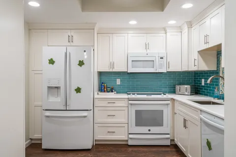 a kitchen with white cabinets and white appliances