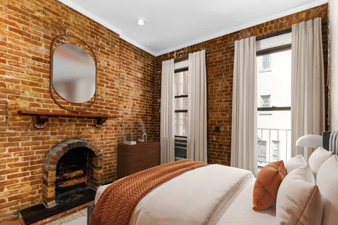 a bedroom with a bed a fireplace and a large window