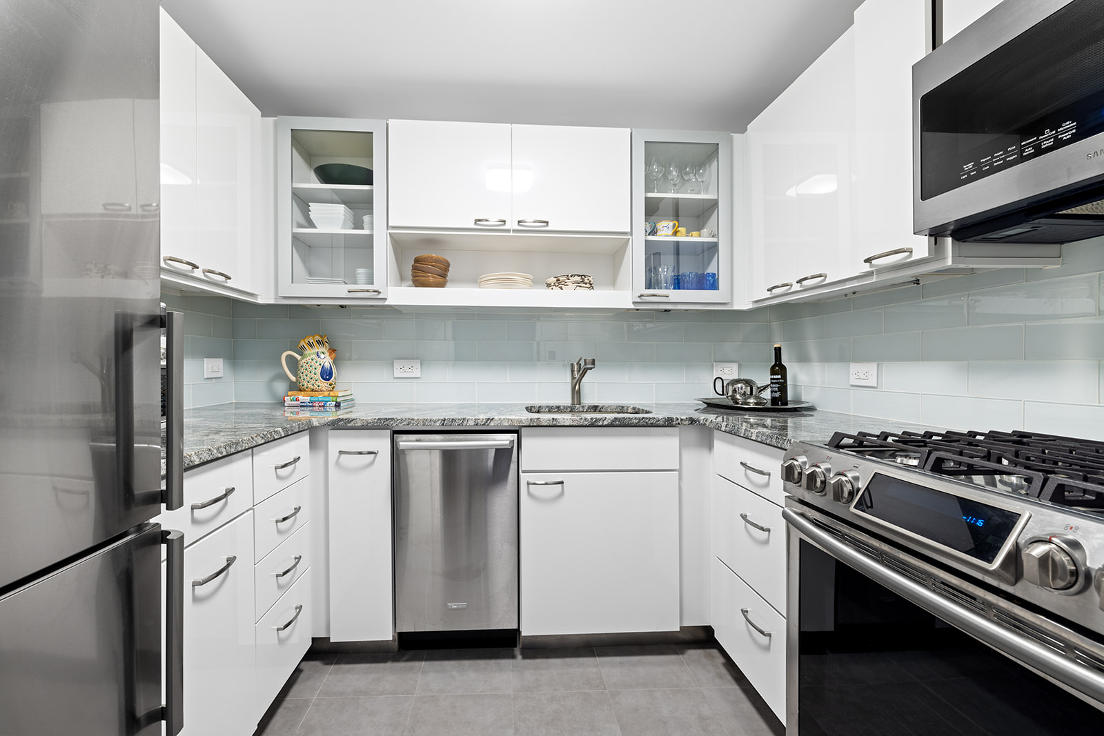 188 East 70th Street, Unit 8E Manhattan, NY 10021 - Photo 3 of 10 a white kitchen with stainless steel appliances granite countertop a stove and a sink
