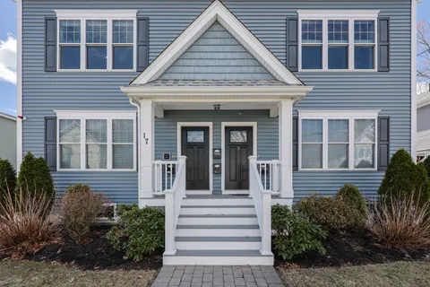 a view of a house with small yard plants and large tree
