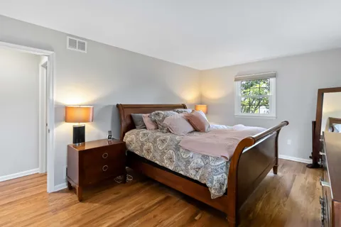 a bedroom with a bed and a dresser next to a window