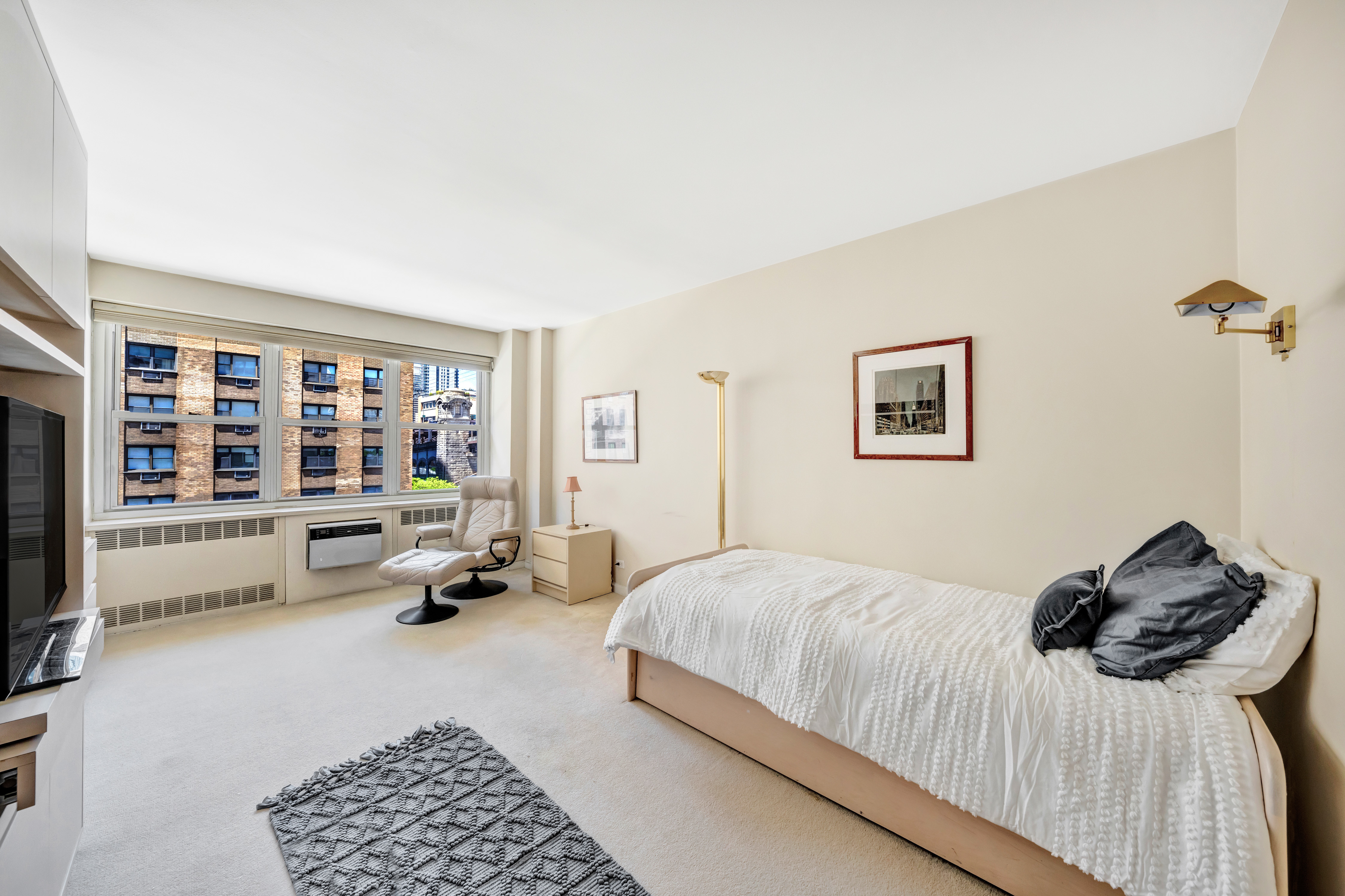 35 Sutton Place, Unit 7E Manhattan, NY 10022 - Photo 10 of 18 a bedroom with a bed and a couch next to a window