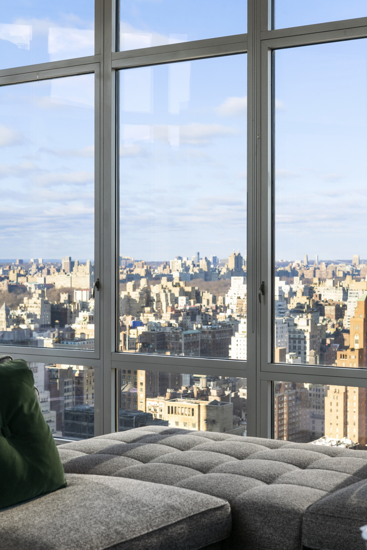 207 East 57th Street, Unit 34A Manhattan, NY 10022 - Photo 6 of 22 a living room filled with couches and a dining table with a glass window