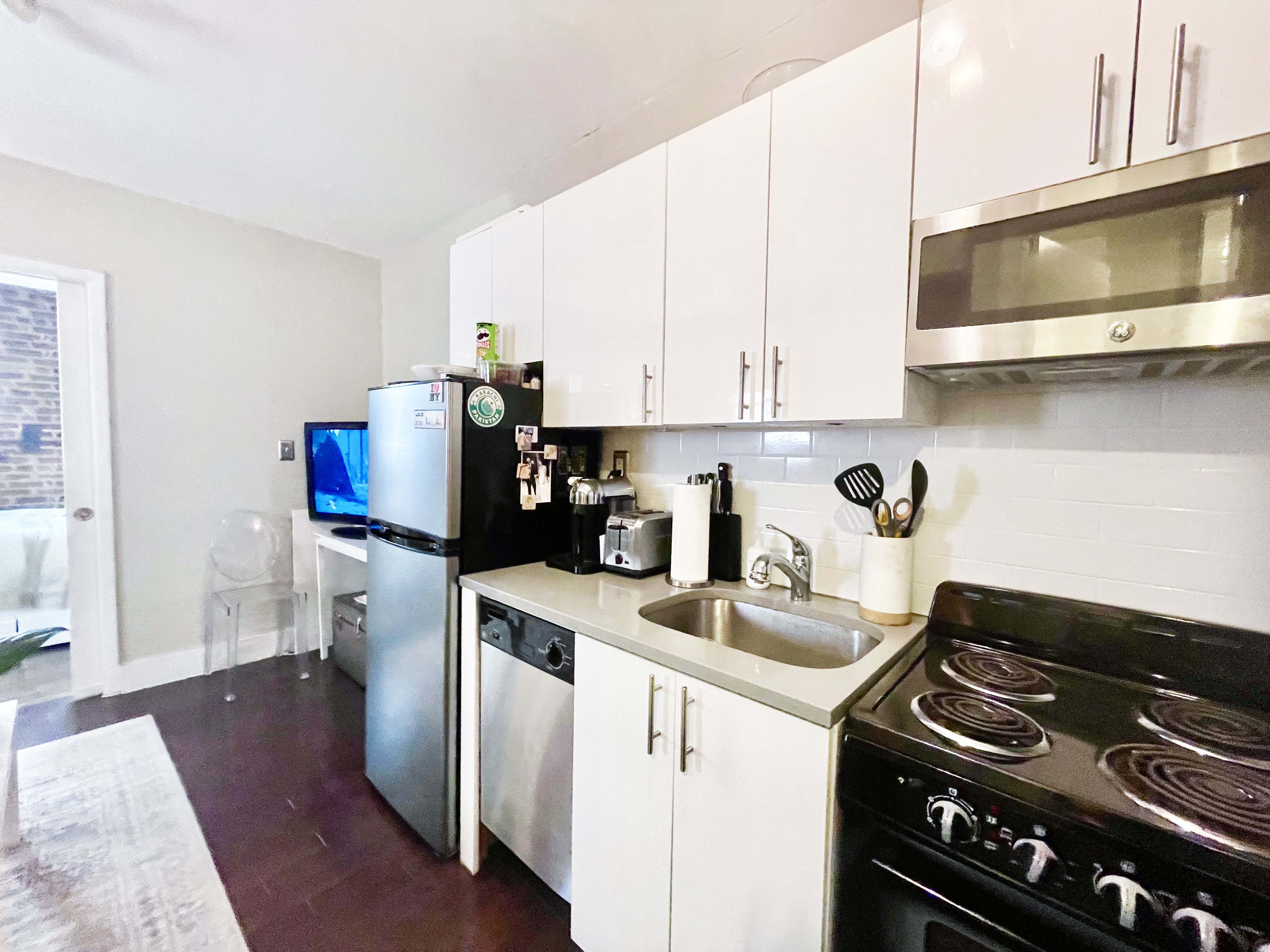 57 Spring Street, Unit 6 Manhattan, NY 10012 - Photo 7 of 10 a kitchen with stainless steel appliances granite countertop a stove a sink and a microwave