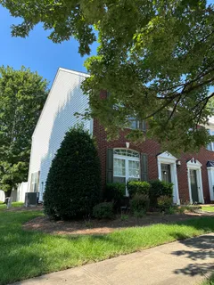 a view of a house with a yard and a large tree