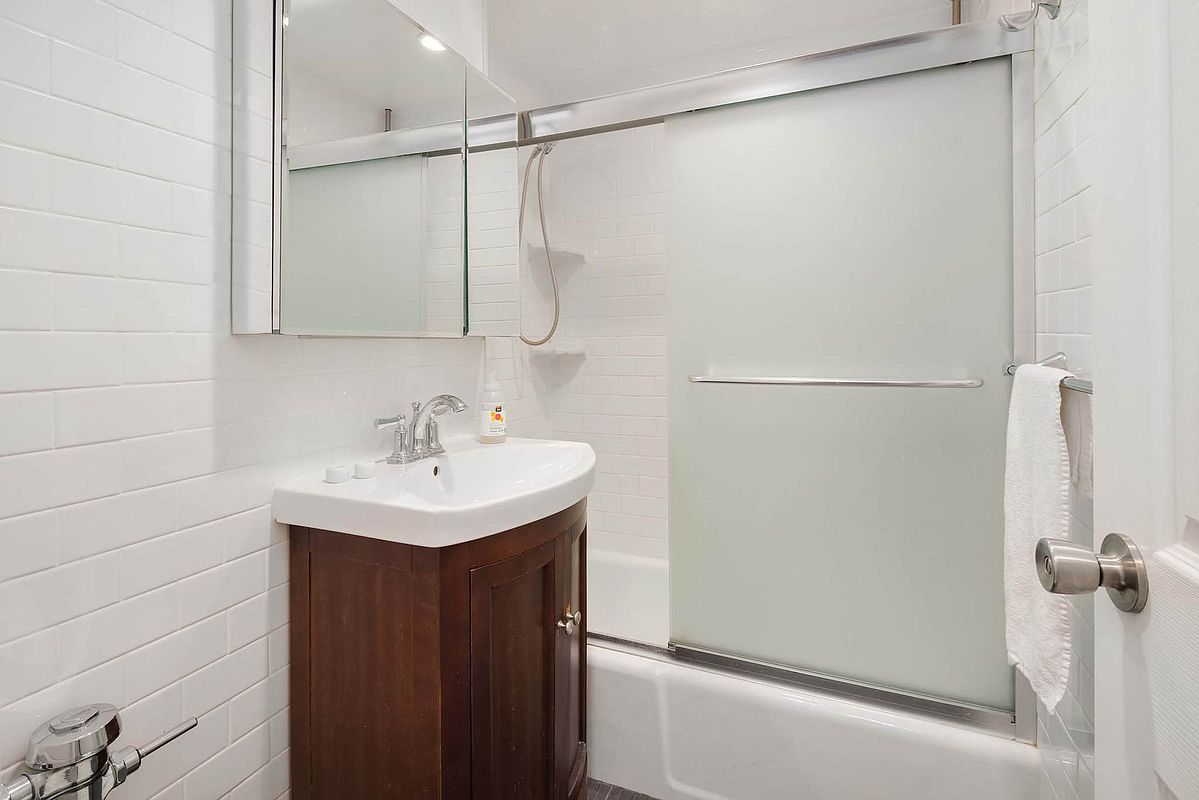 215 East 77th Street, Unit 4C Manhattan, NY 10075 - Photo 6 of 7 a bathroom with a sink a shower and a sink