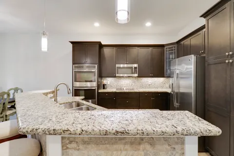a kitchen with kitchen island granite countertop a sink refrigerator and cabinets