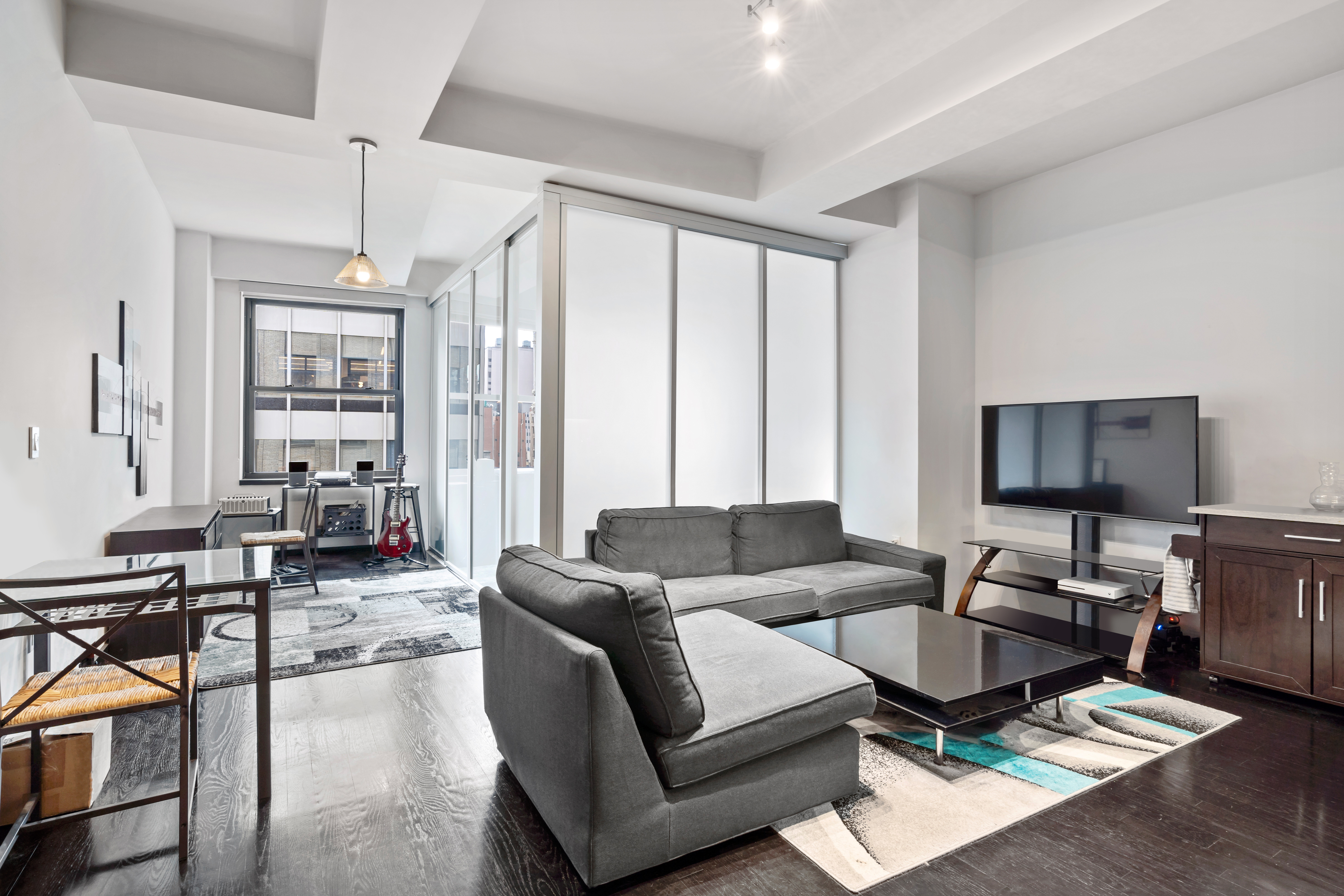 20 Pine Street, Unit 2012 Manhattan, NY 10005 - Photo 3 of 25 a living room with furniture a flat screen tv and a window