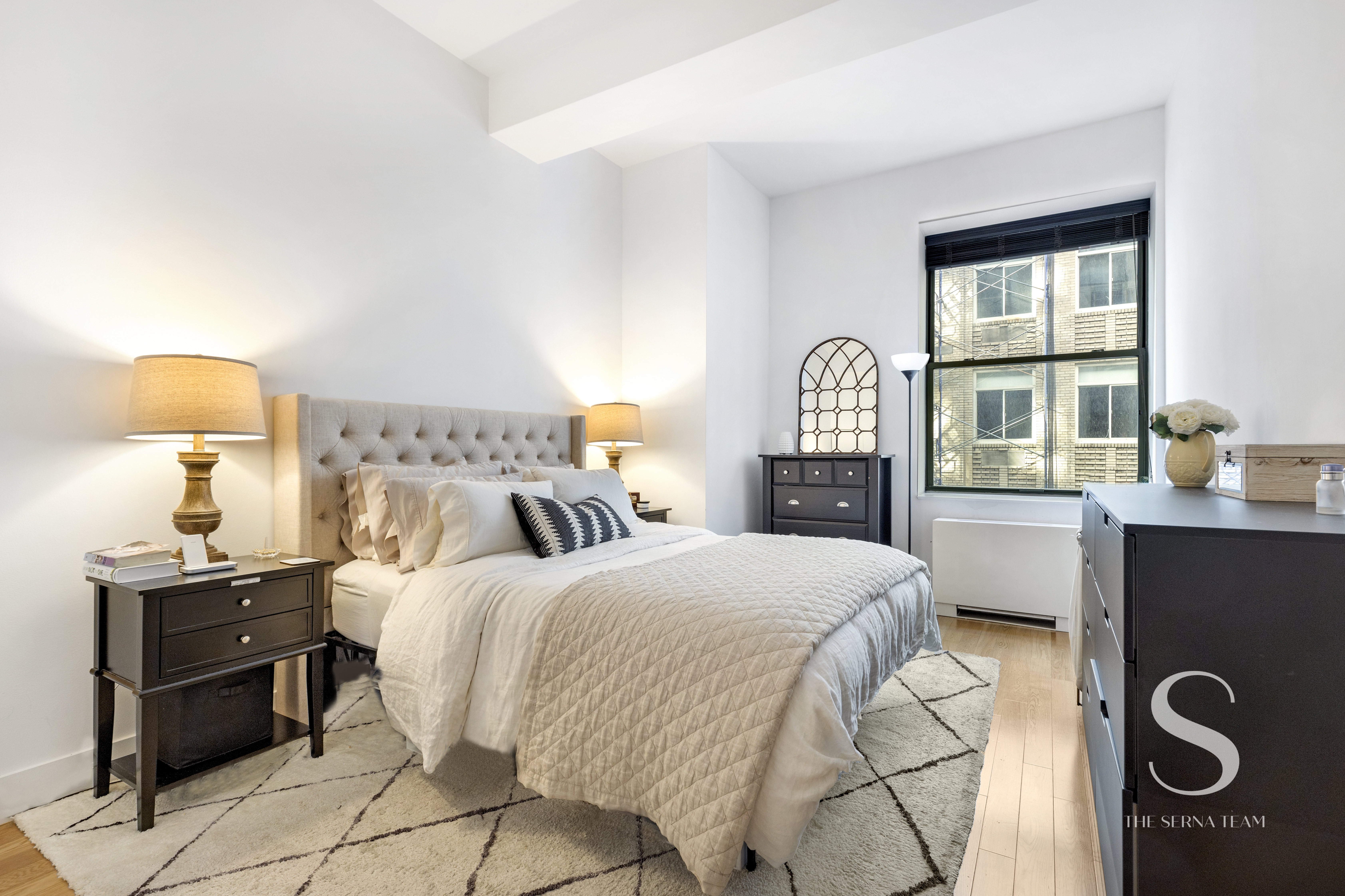 99 John Street, Unit 910 Manhattan, NY 10038 - Photo 5 of 11 a bedroom with a bed and a lamp next to a window