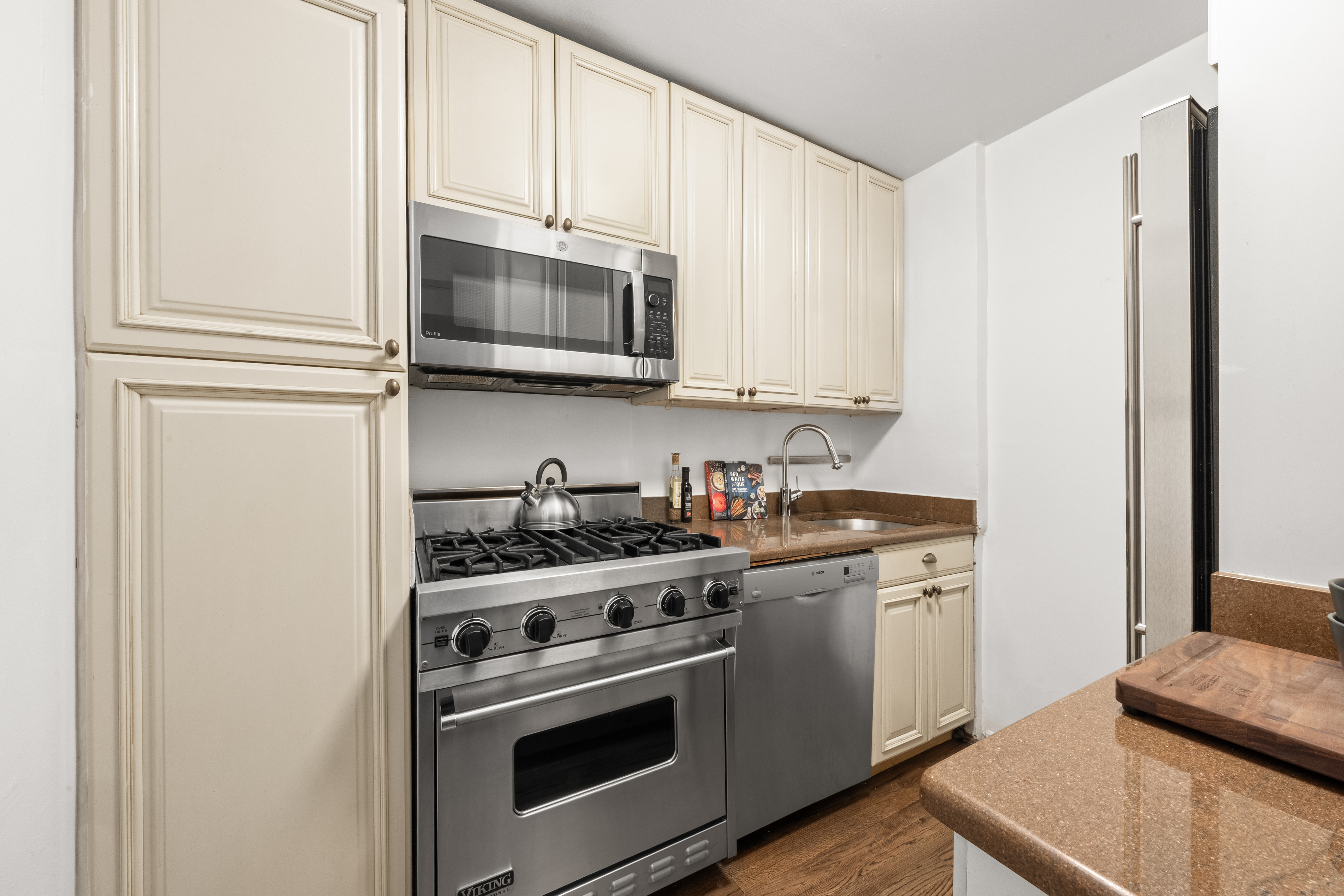 140 7th Avenue, Unit 4M Manhattan, NY 10011 - Photo 4 of 8 a kitchen with stainless steel appliances granite countertop a stove a microwave and a refrigerator