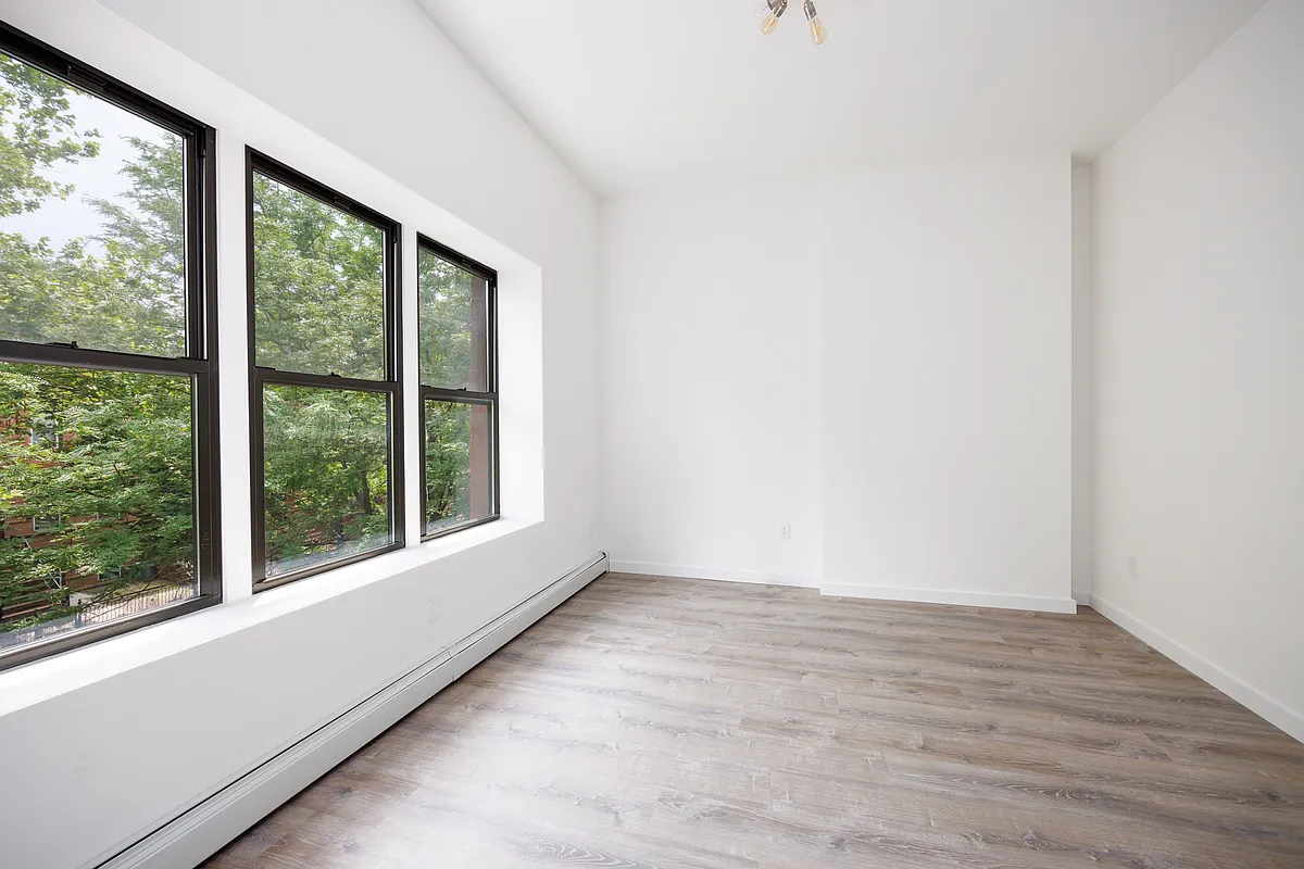 601 Decatur Street Brooklyn, NY 11233 - Photo 4 of 5 a view of an empty room with wooden floor and a window