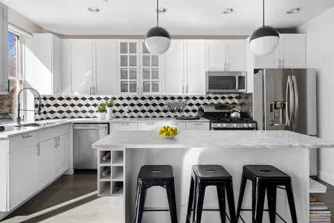 a kitchen with stainless steel appliances a dining table chairs and a refrigerator