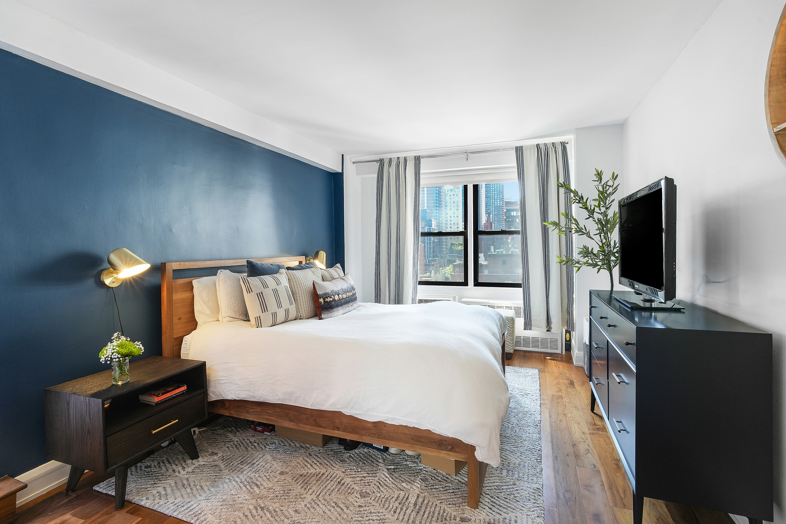 220 East 54th Street, Unit 11H Manhattan, NY 10022 - Photo 7 of 13 a bedroom with a bed and a flat tv screen on dresser