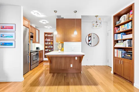 a living room with stainless steel appliances furniture a large window and a bookshelf