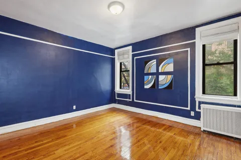 a view of an empty room with window wooden floor and a kitchen