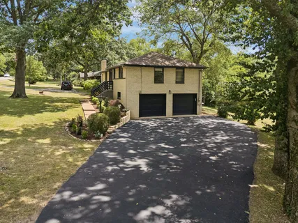a front view of a house with a large tree and yard