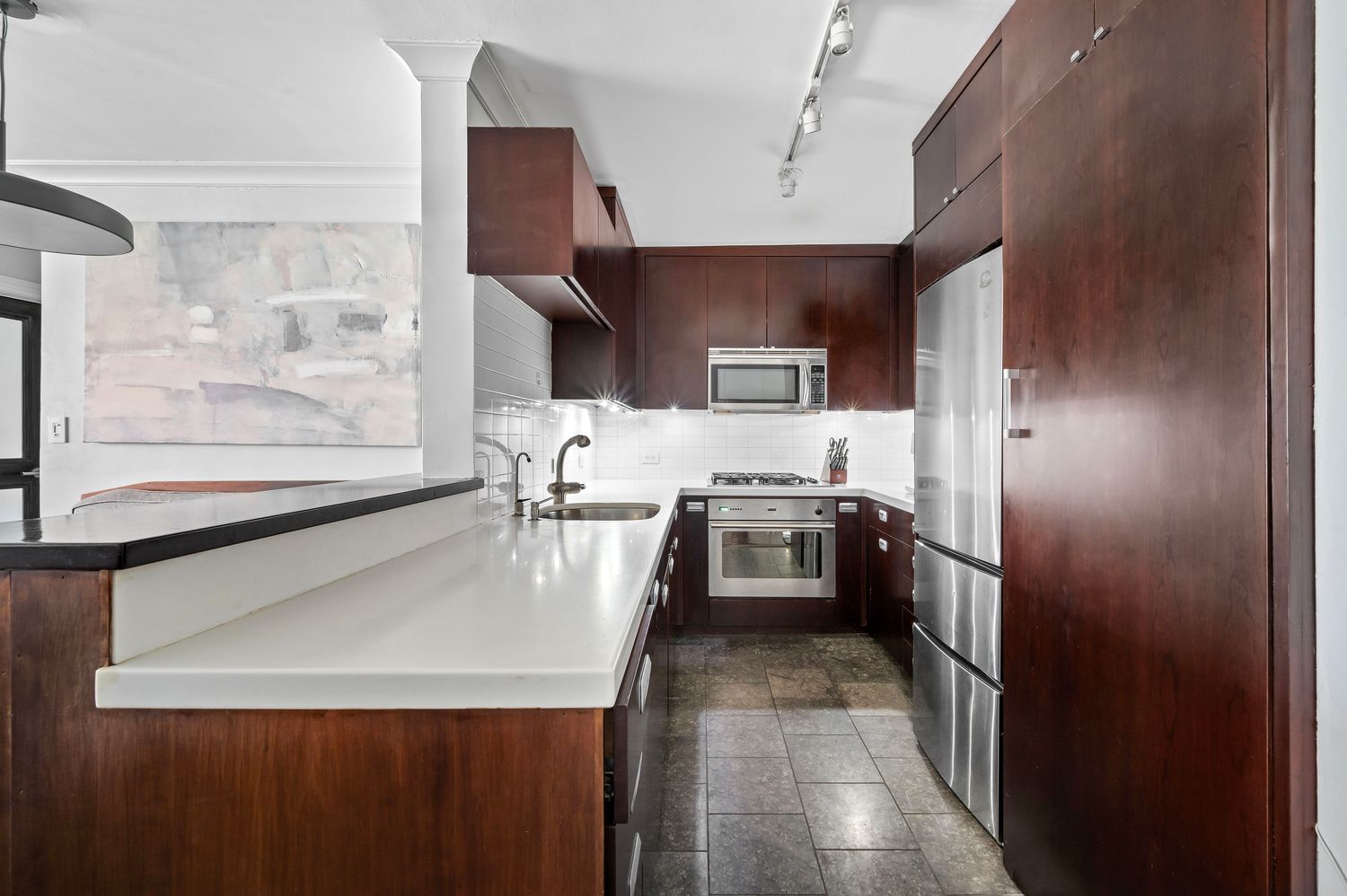 a kitchen with stainless steel appliances a refrigerator a sink a stove and white cabinets