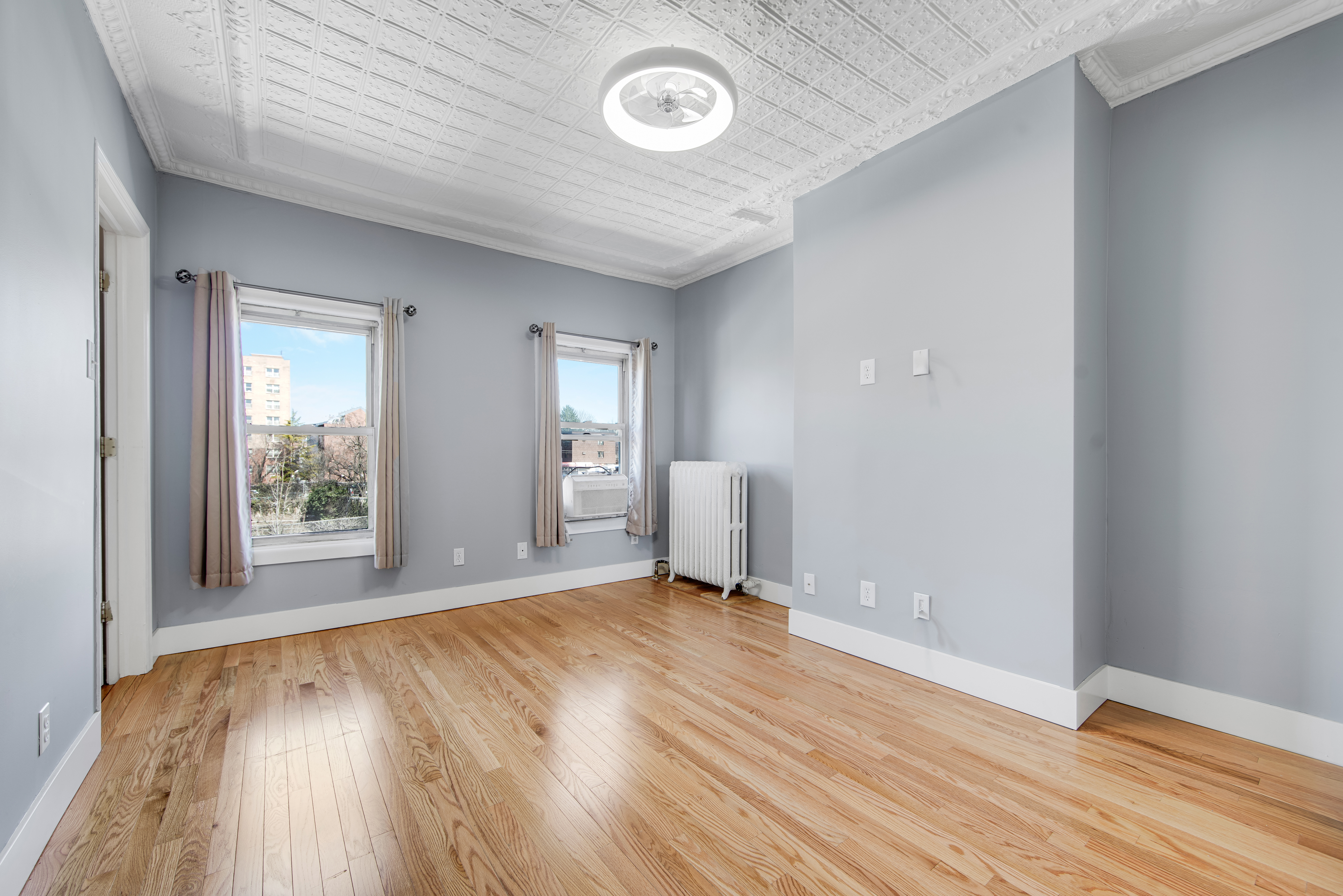 a view of an empty room with wooden floor and a window