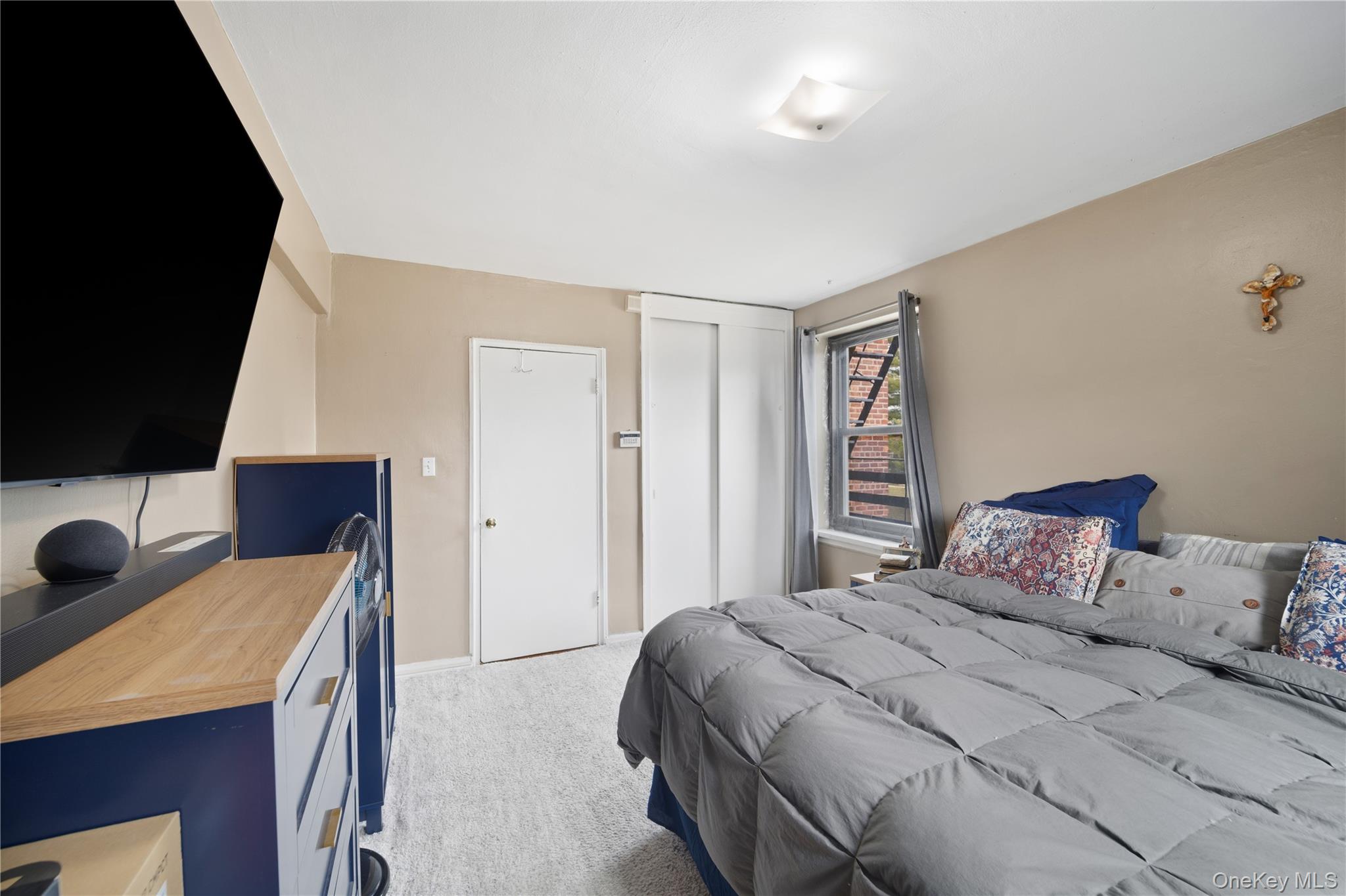 73-11 Bell Boulevard, Unit 2C Queens, NY 11364 - Photo 5 of 16 a bedroom with a bed and a flat tv screen on dresser