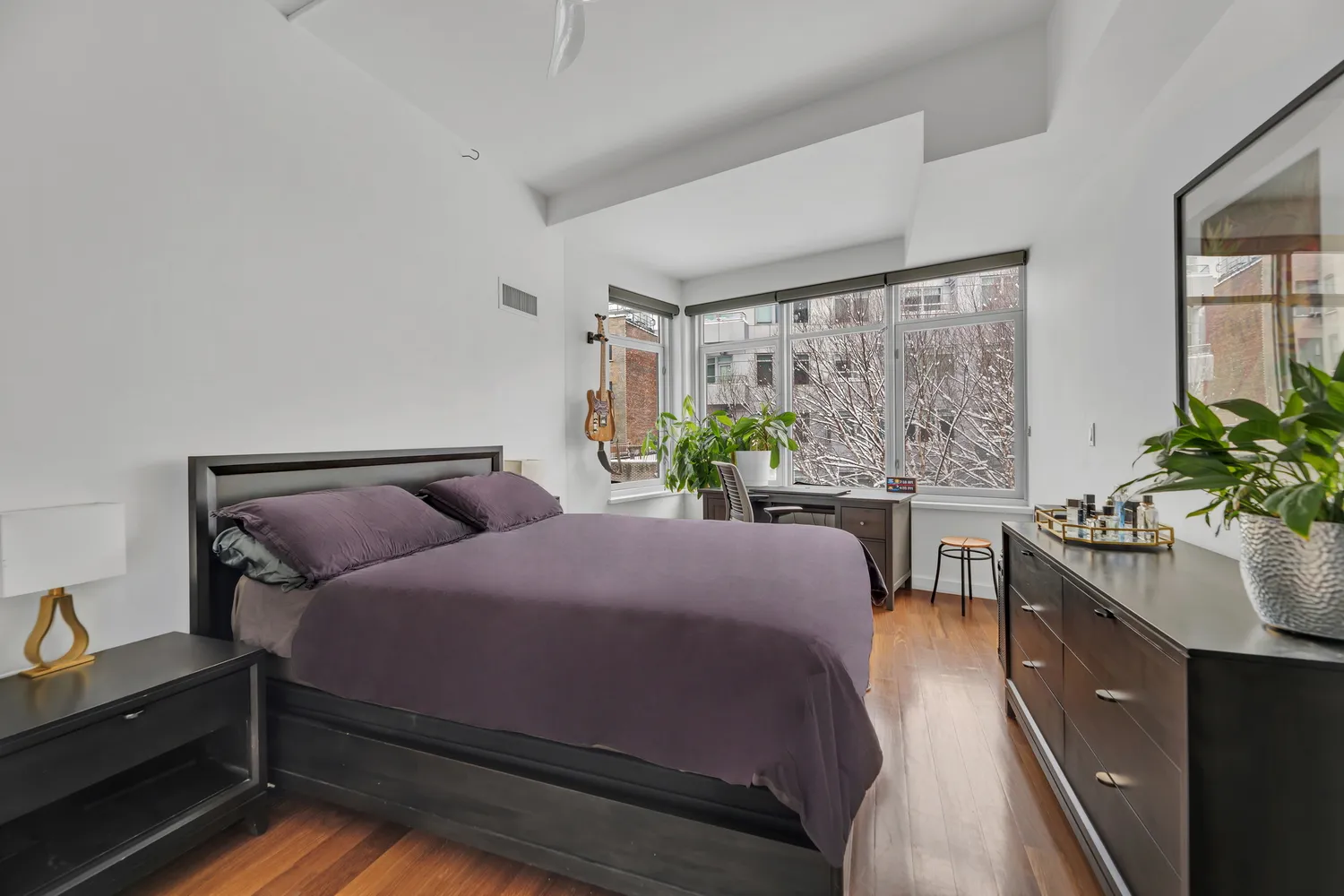 a bedroom with a bed table flowerpot and window