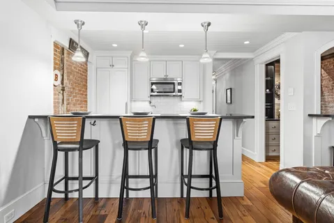 a kitchen with stainless steel appliances kitchen island granite countertop a table chairs and a refrigerator