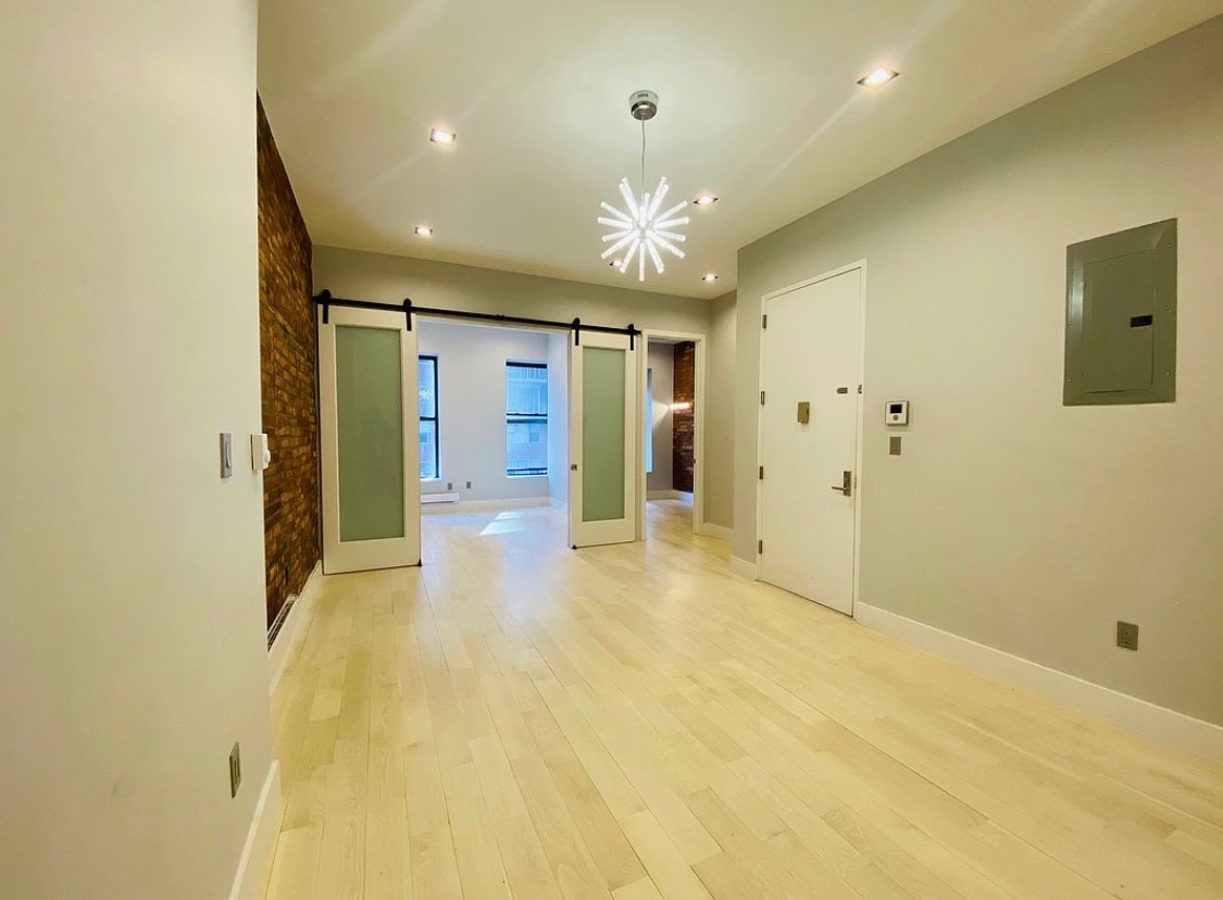 133 East 35th Street, Unit 3 Manhattan, NY 10016 - Photo 6 of 16 a view of an empty room with kitchen and chandelier