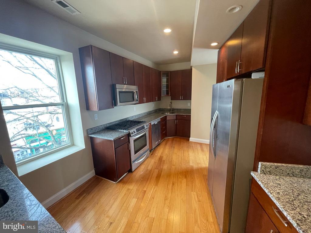 1033 Park Road Northwest, Unit 6 Washington, DC 20010 - Photo 7 of 38 a kitchen with stainless steel appliances granite countertop a refrigerator a stove a sink and a microwave