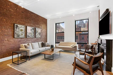 a living room with furniture a flat screen tv and a window