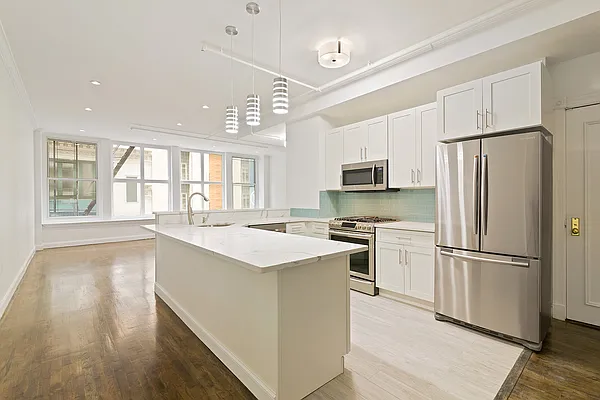 a kitchen with a refrigerator a stove top oven a sink and a island with wooden floor