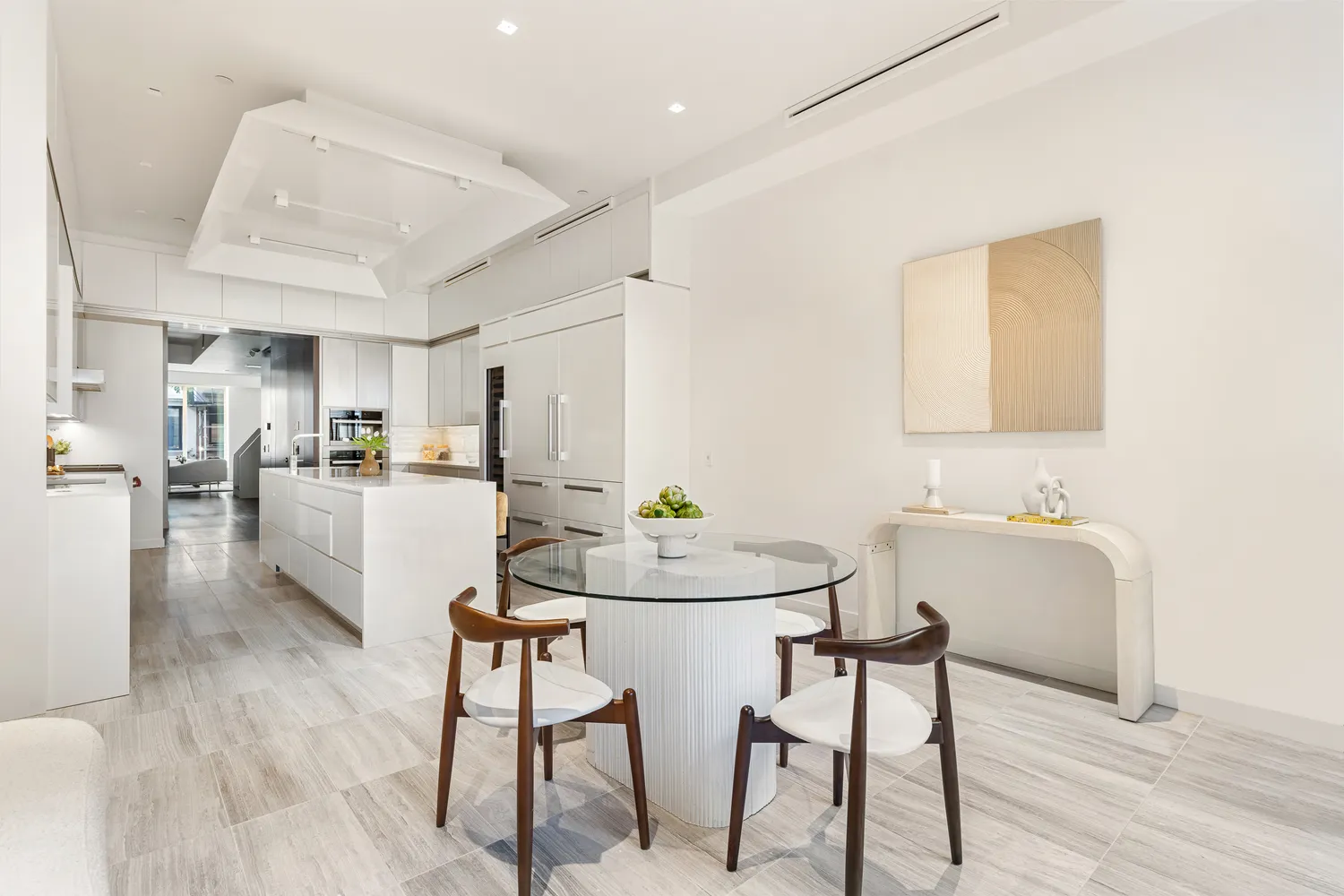 a kitchen with stainless steel appliances kitchen island granite countertop a dining table chairs and a refrigerator