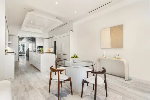 a kitchen with stainless steel appliances kitchen island granite countertop a dining table chairs and a refrigerator