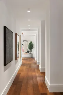 a view of a hallway with wooden floor and a living room