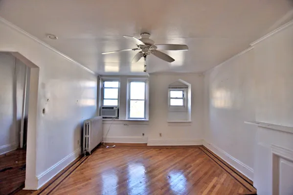 a view of an empty room with a window and wooden floor