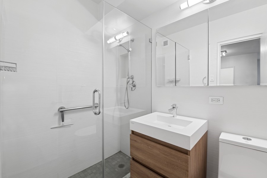 30 West 60th Street, Unit 6K Manhattan, NY 10019 - Photo 4 of 5 a bathroom with a sink a mirror and shower