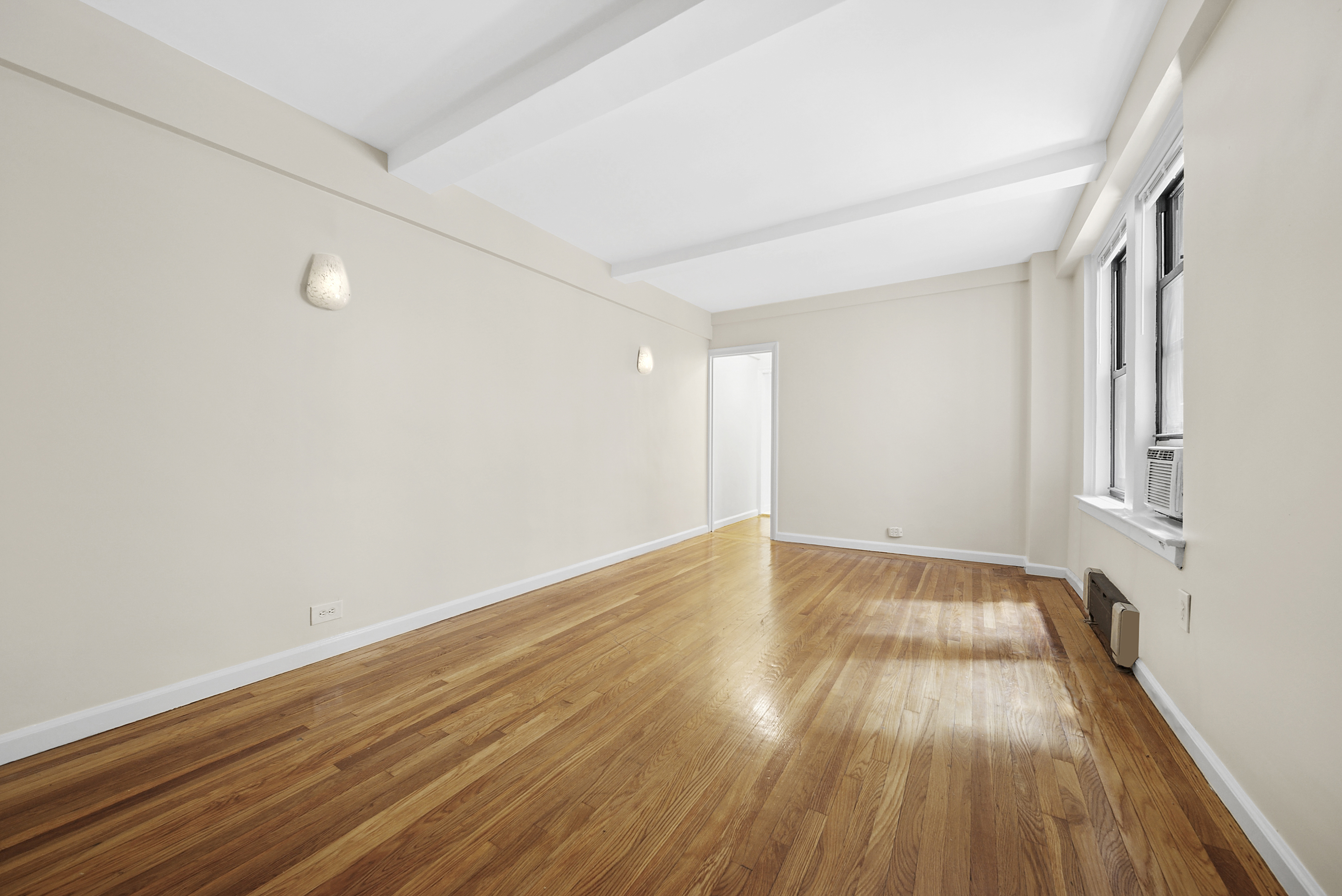 321 East 54th Street, Unit 2E Manhattan, NY 10022 - Photo 2 of 7 a view of an empty room with wooden floor and a window