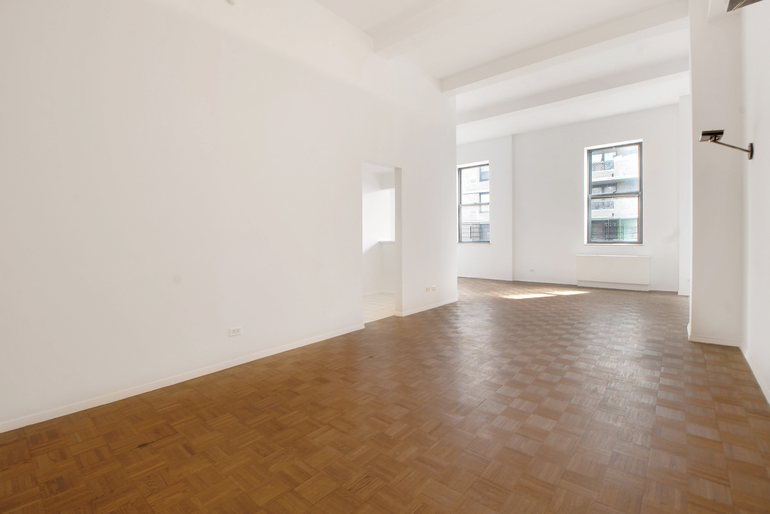 1255 5th Avenue, Unit 5J Manhattan, NY 10029 - Photo 5 of 17 an empty room with wooden floor and windows