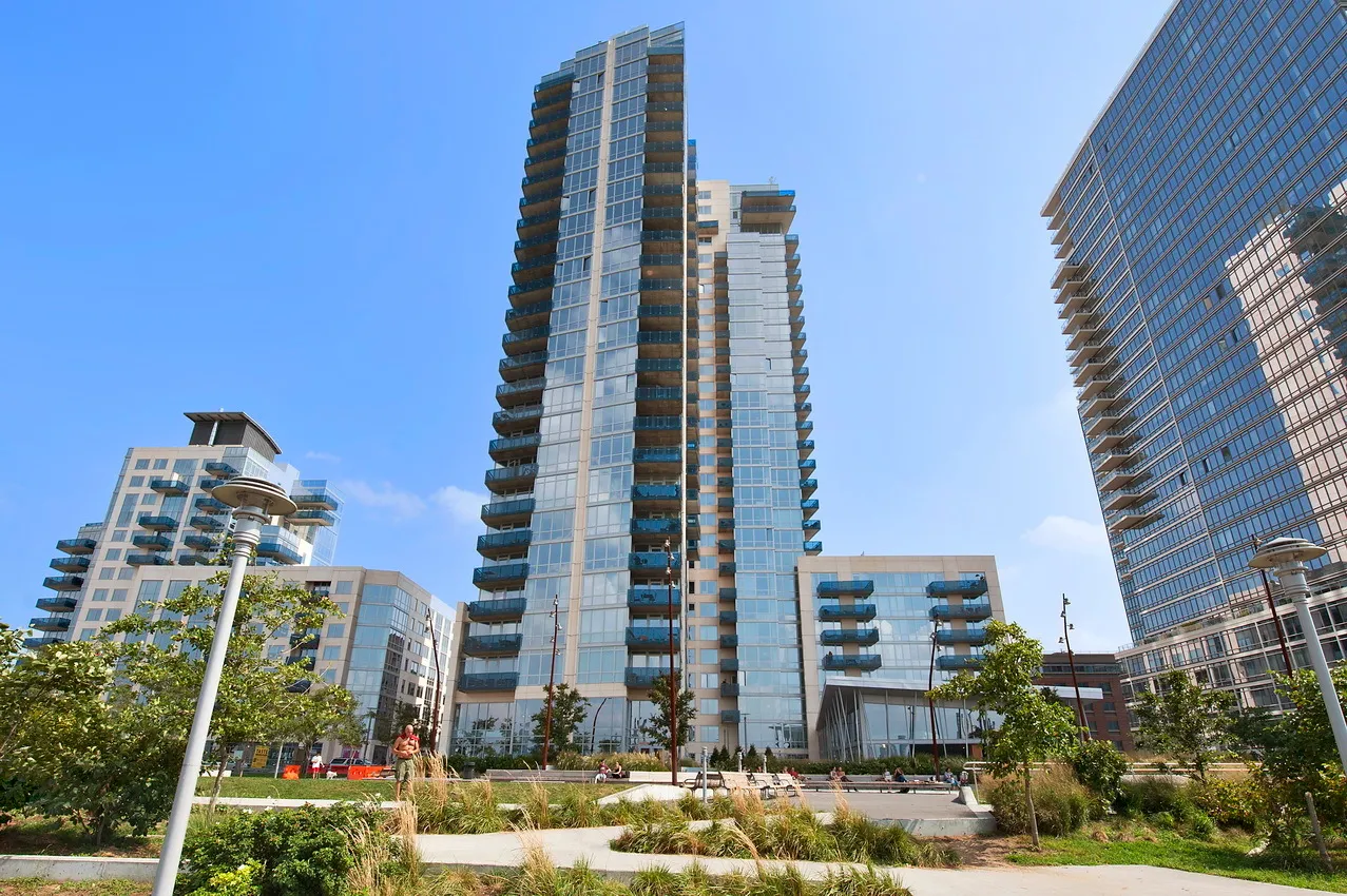 a front view of multi story residential apartment building with yard and parking space