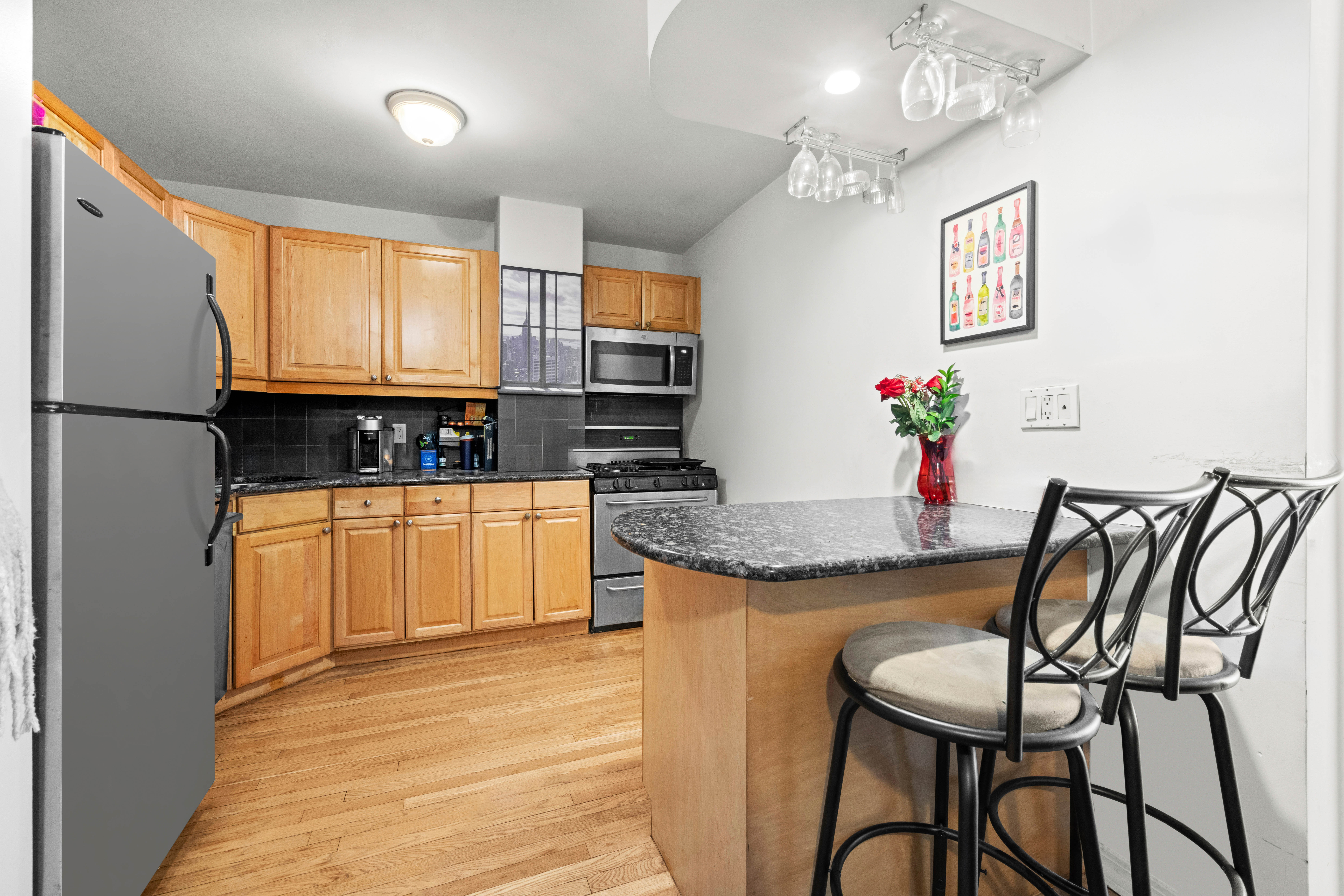 333 East 34th Street, Unit 5E Manhattan, NY 10016 - Photo 5 of 13 a kitchen with granite countertop a table chairs stove and cabinets