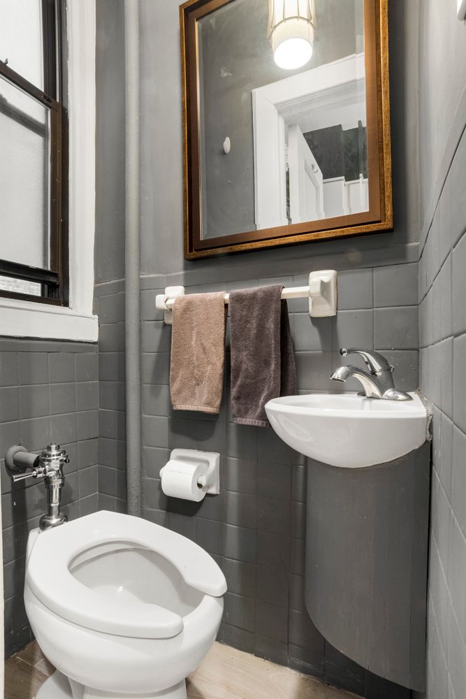 114 West 70th Street, Unit 3D Manhattan, NY 10023 - Photo 6 of 9 a bathroom with a toilet a sink and mirror