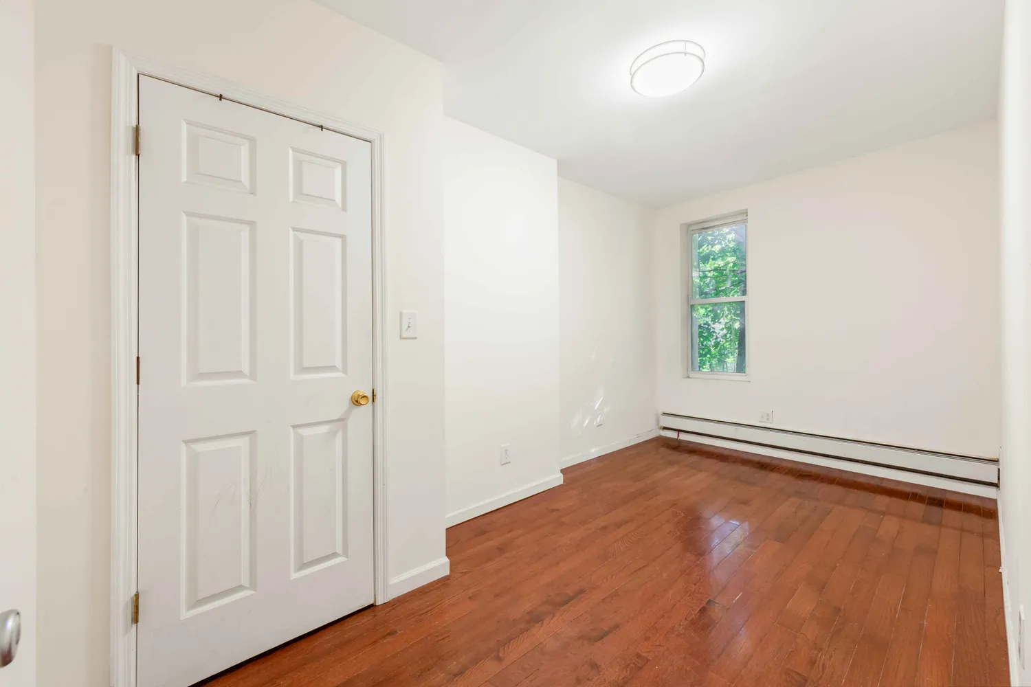 an empty room with wooden floor closet and windows