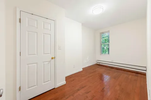 an empty room with wooden floor closet and windows