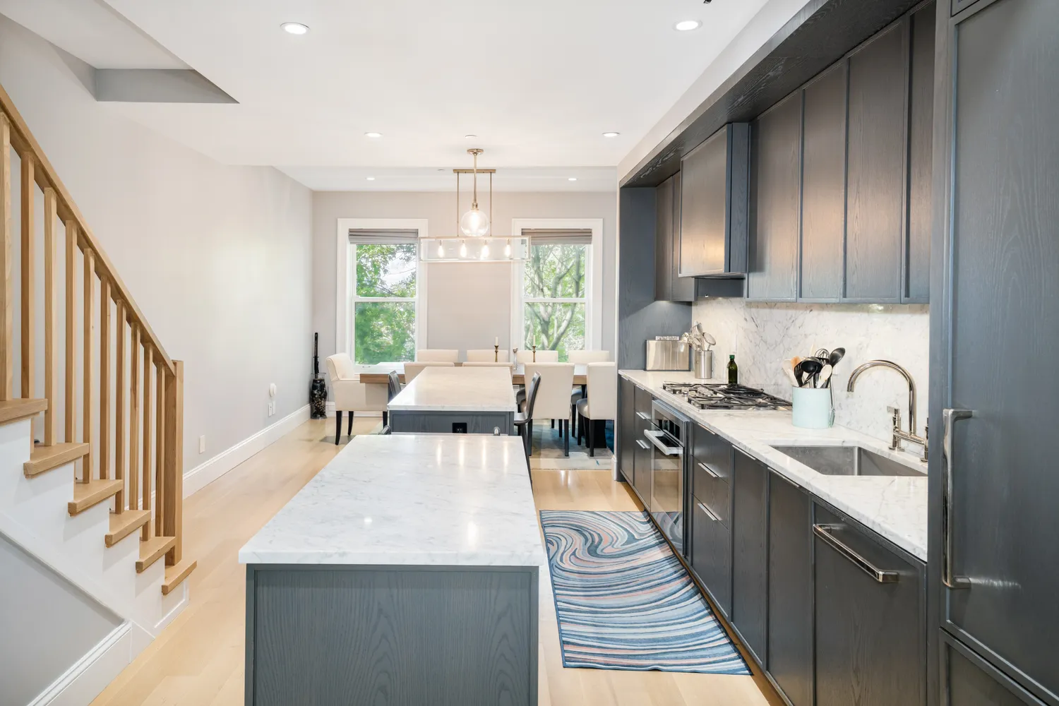 a large kitchen with stainless steel appliances a sink dishwasher a stove a dining table and chairs with wooden floor