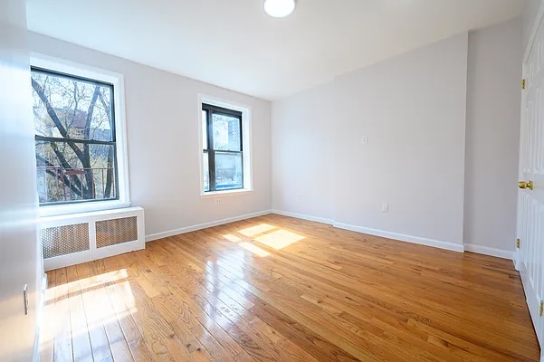237 West 135th Street, Unit 3A Manhattan, NY 10030 - Photo 8 of 12 an empty room with wooden floor and windows
