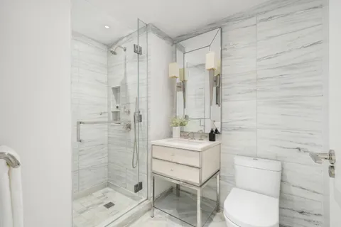 a bathroom with a toilet a sink a shower and mirror