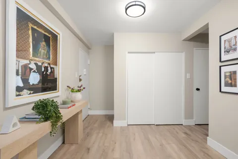 a view of a hallway with wooden floor and a potted plant