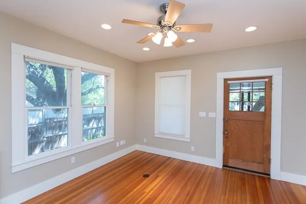 an empty room with wooden floor and windows