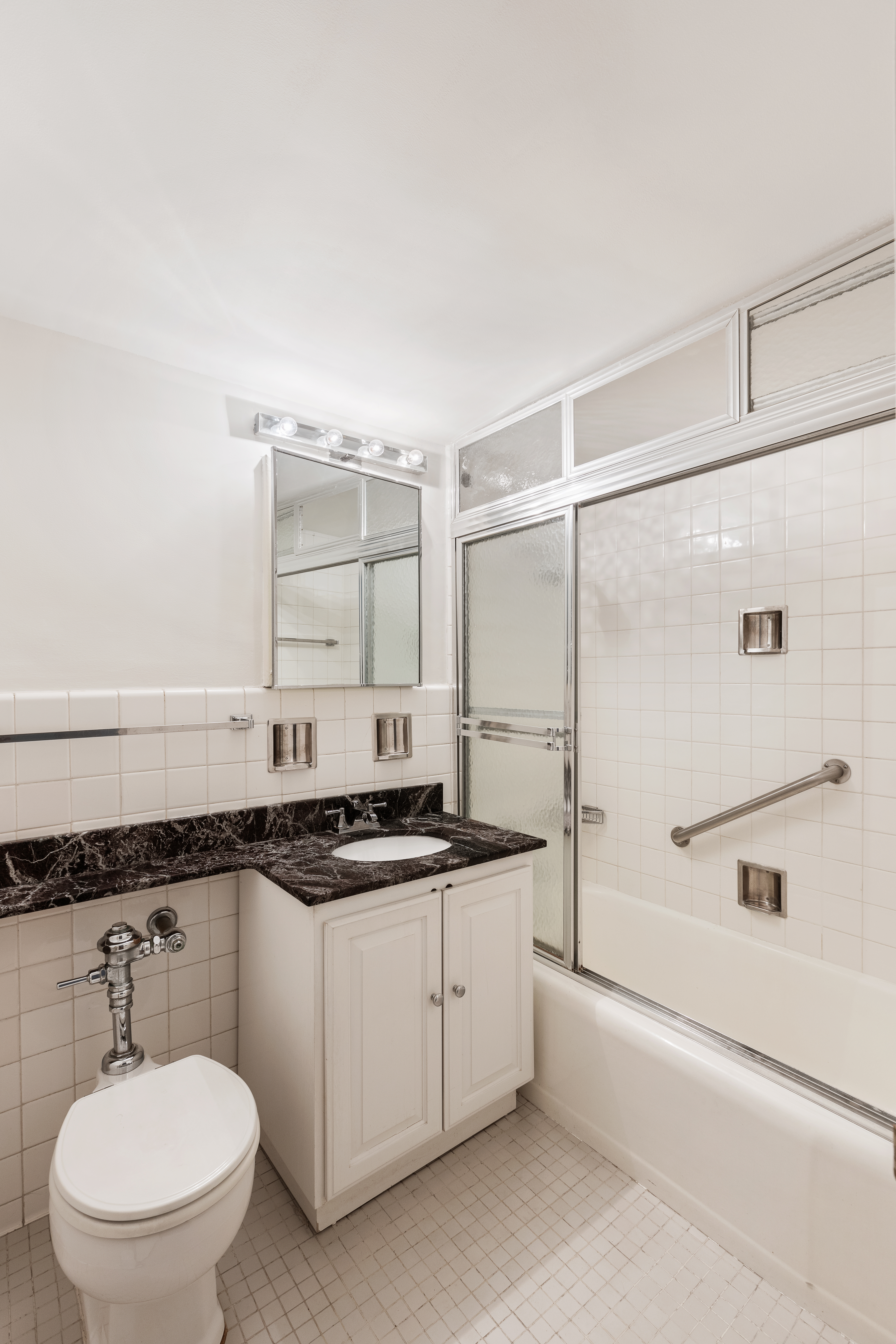 70 East 10th Street, Unit 3M Manhattan, NY 10003 - Photo 6 of 14 a bathroom with a granite countertop sink mirror vanity and toilet