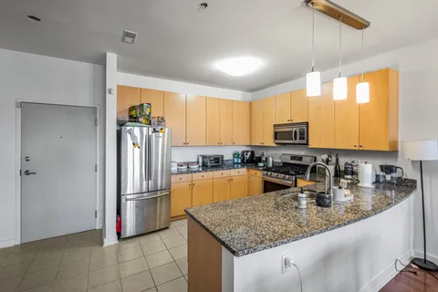 a kitchen with stainless steel appliances granite countertop a refrigerator a sink a stove a microwave and island