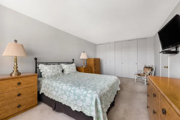 a bedroom with a bed and a flat tv screen on the dresser