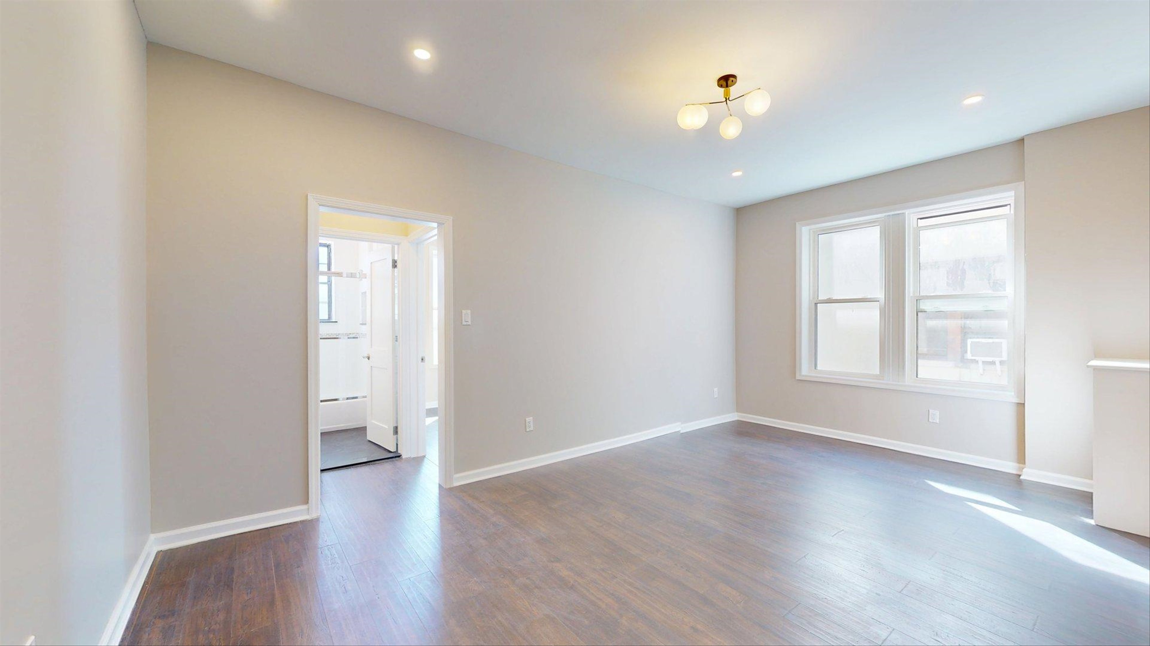 7609 4th Avenue, Unit E14 Brooklyn, NY 11209 - Photo 5 of 15 an empty room with wooden floor and windows